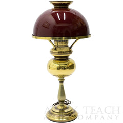A vintage hurricane lamp with a dark red shade and golden base.